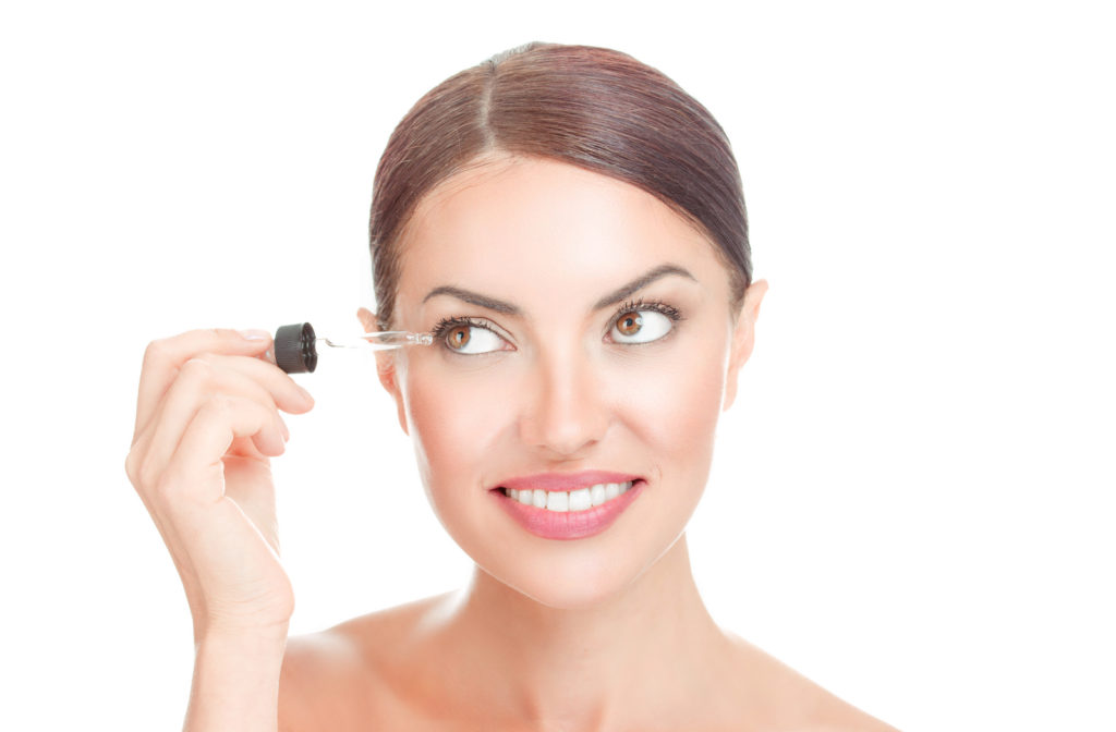 Woman looking at eyelash serum prior to applying to eyelash