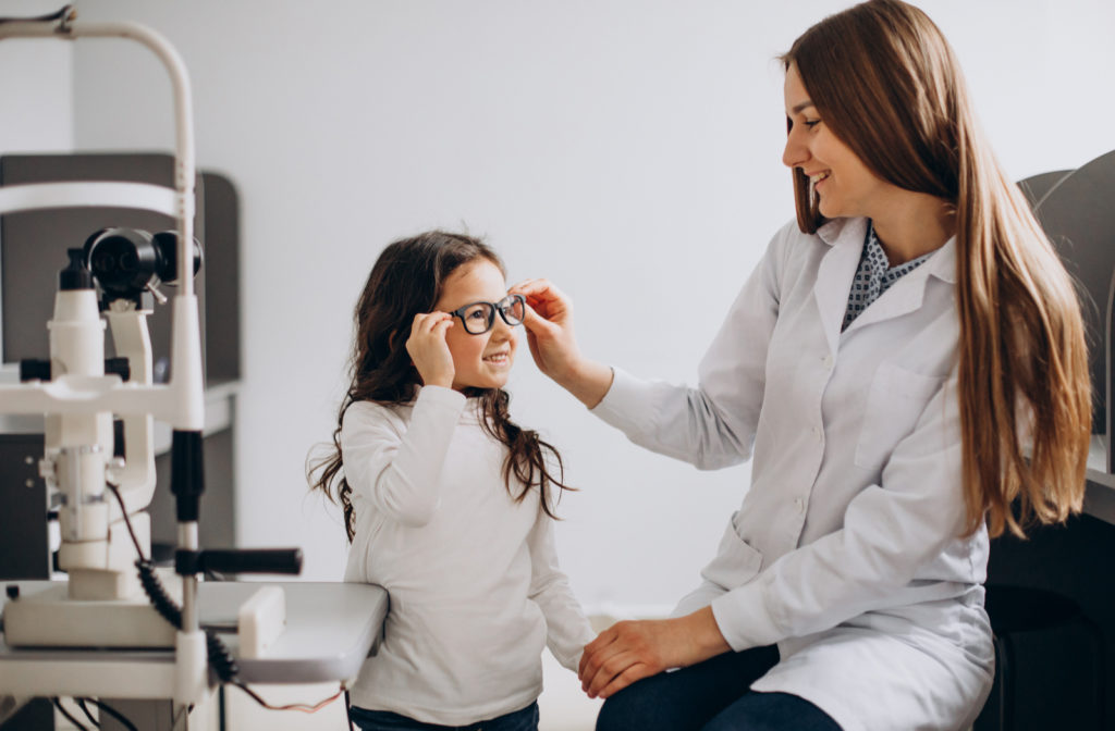 Optometrist helping young girl with myopia need by suggesting corrective lenses for her eyes