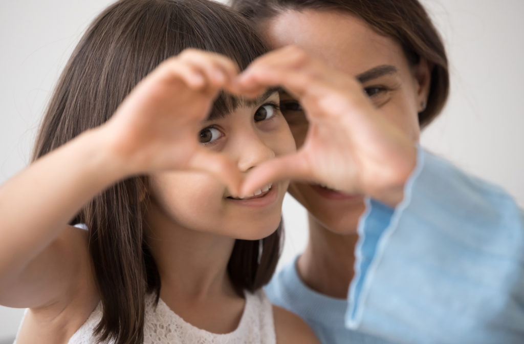 Mother and daughter creating heart around eye to signify healthy vision
