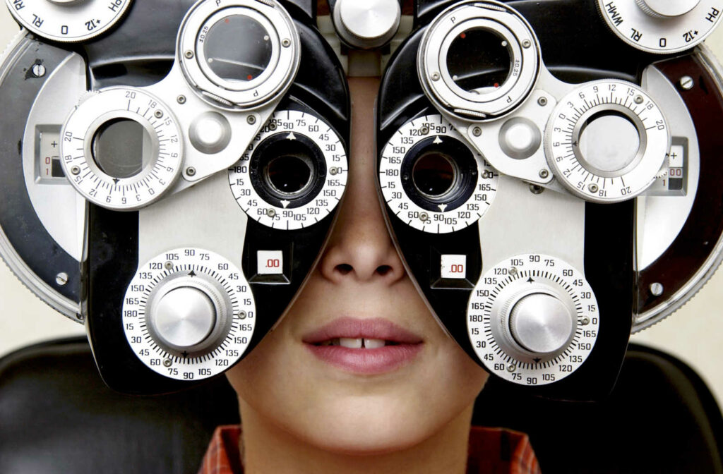 A young patient looks through a phoropter during an eye exam.