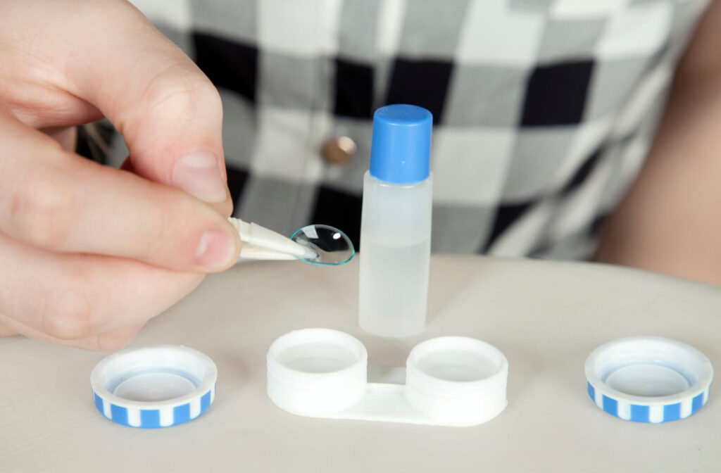 A close-up of a person's hand properly storing the contact lenses in a container after cleaning with a solution before dipping into the water for swimming.