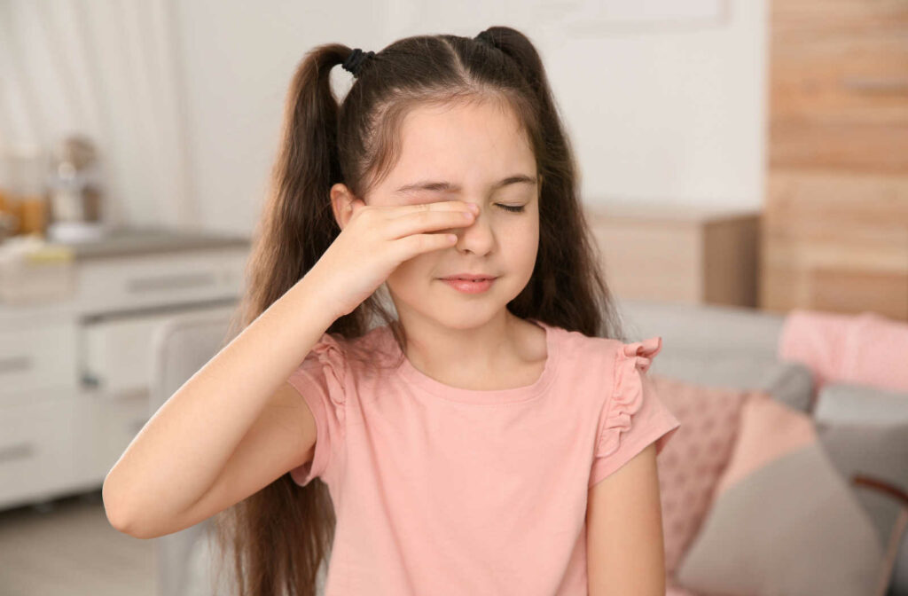 A young girl rubbing her eye as she suffers from discomfort due to an eye infection.