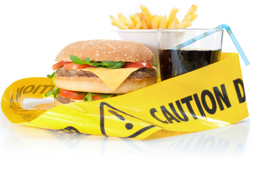 A hamburger, french fries, and cup of soda with caution tape around them.