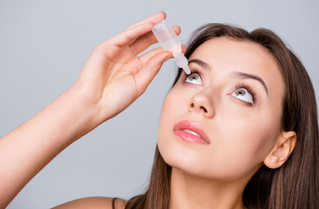 A woman applying eye drops in her eye. 