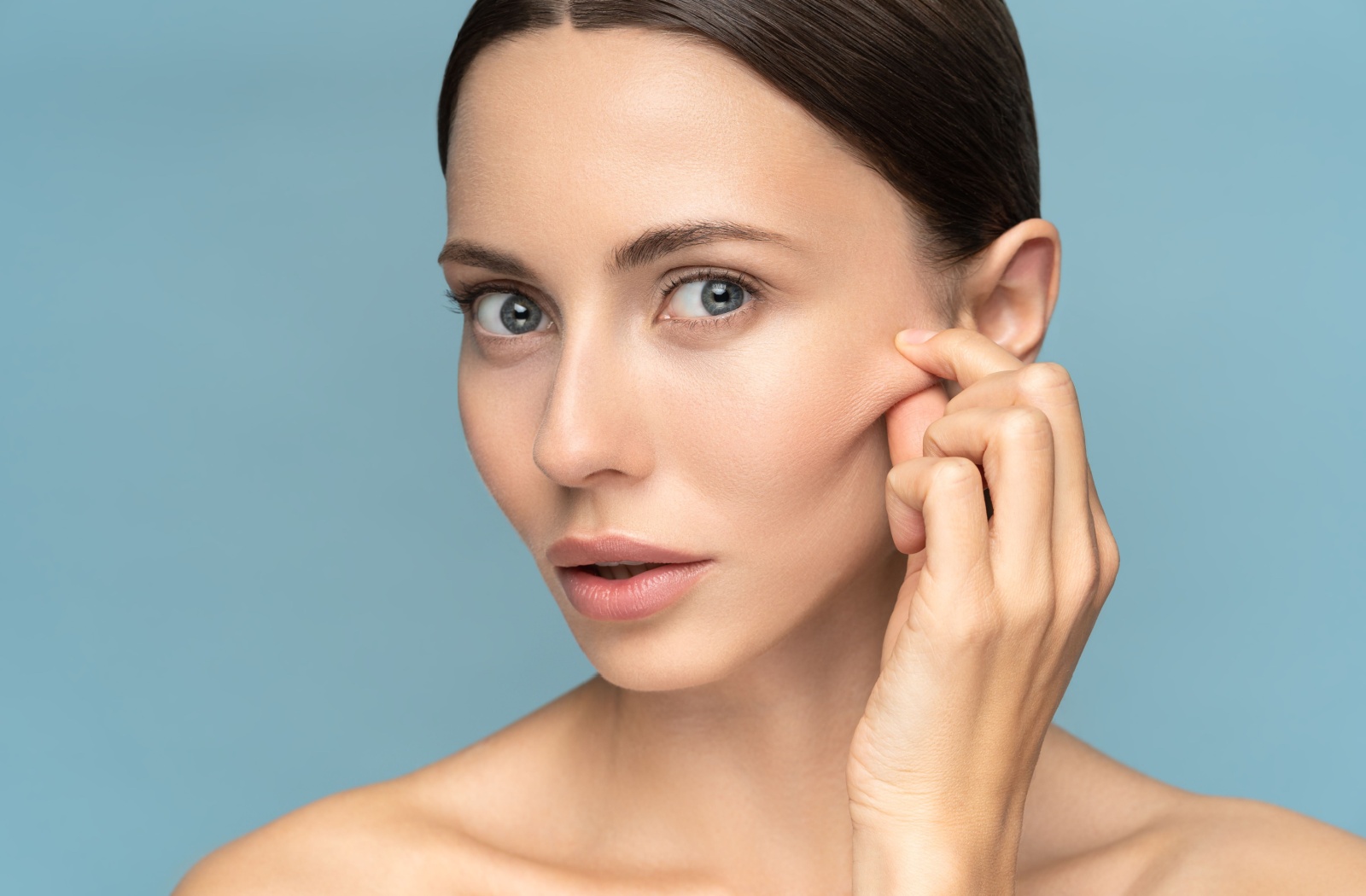 A woman pinching a portion of loose skin on her face