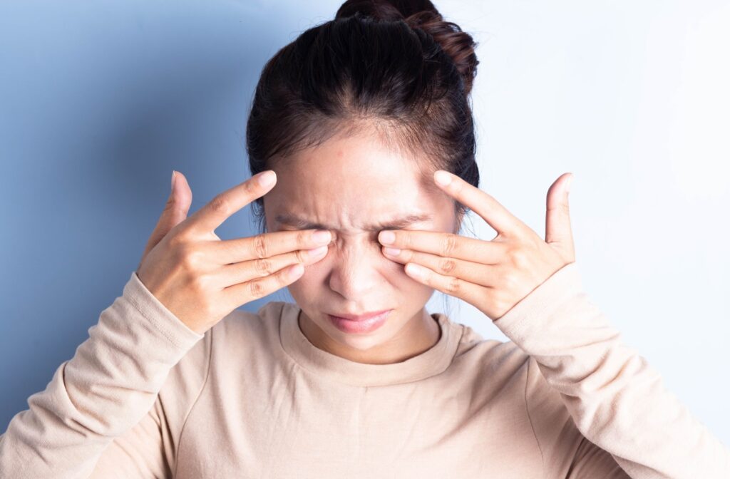 A close-up image of a young woman rubbing her eyes to relieve dry eye discomfort.