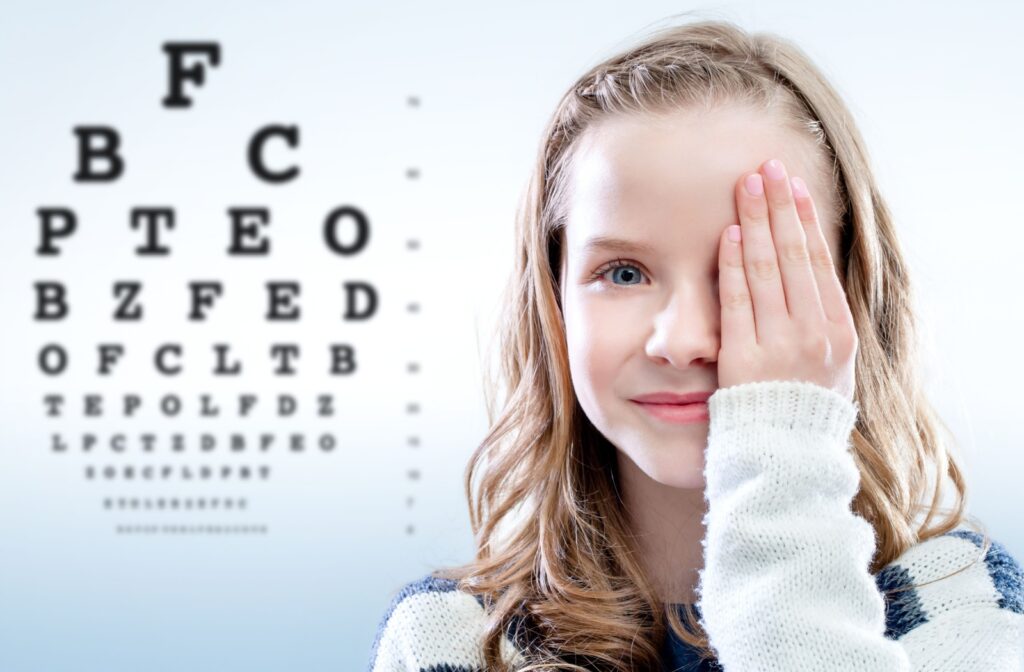 Close up portrait of girl reviewing eyesight closing eye with hand. Out of focus test chart in background.