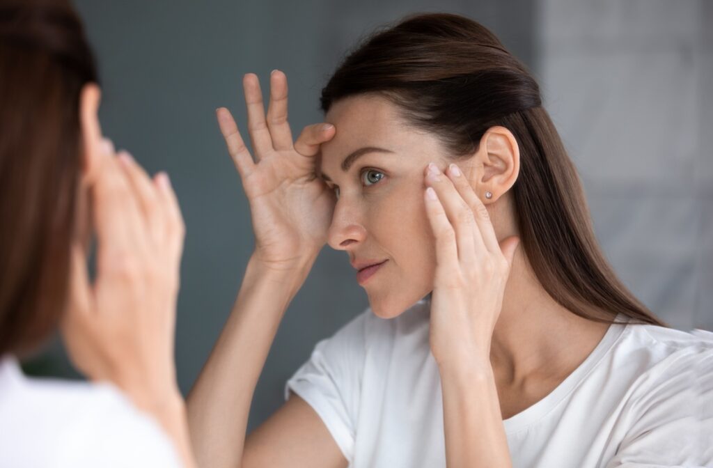 An adult checking their skin in the mirror and considering skin tightening treatments.