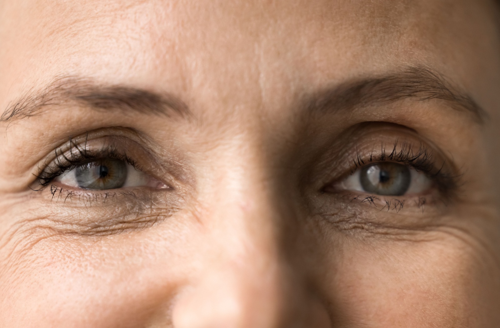 Close-up of a mature woman's eyes showing fine lines and natural skin texture around the eye area.